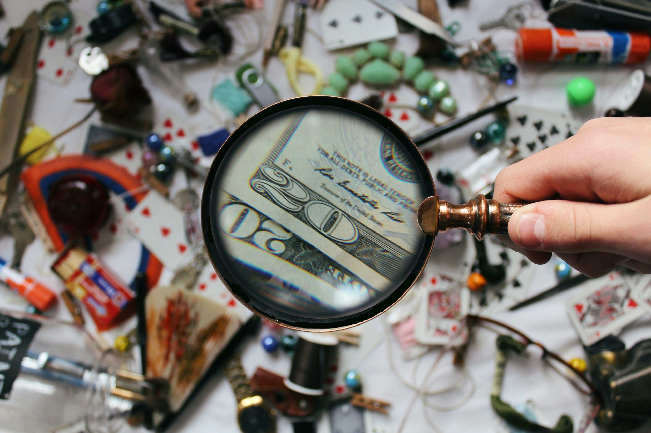 A magnifying glass over money in a jumble of items.